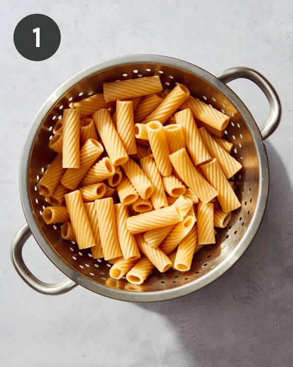 A colander filled with cooked rigatoni.