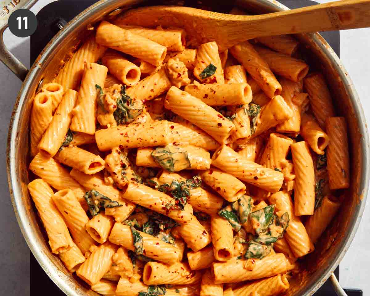 Red pepper flakes sprinkled on a rigatoni pasta dish in a skillet.