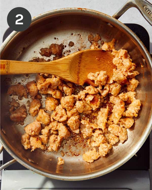 A skilled with a wood spoon cooking Italian sausage.