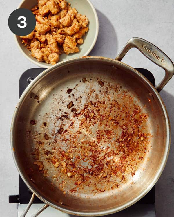 A bowl of cooked Italian sausage on the side of a skillet.