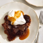 Sticky toffee pudding served onto plates with whipped cream and toffee sauce.