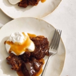 Sticky toffee pudding served onto plates with whipped cream and toffee sauce.
