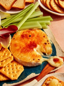 Honey Brûlée Brie on a platter with a knife taking some cheese.