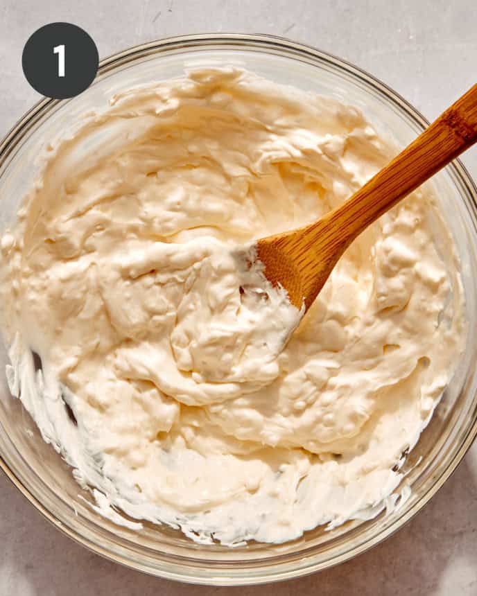 A glass bowl filled with the base of our million dollar dip recipe mixed.