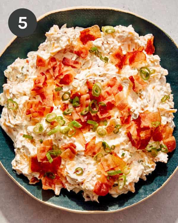 Million dollar dip in a serving bowl with toppings.