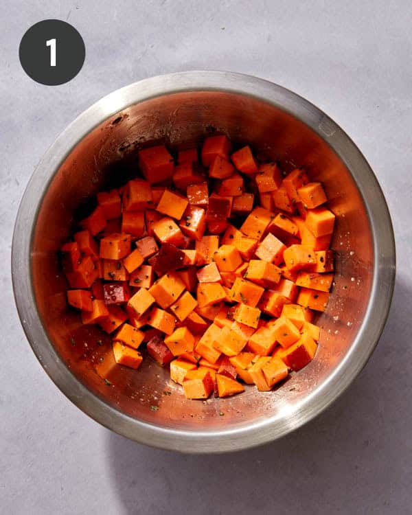 Sweet potatoes in a bowl with oil and seasoning all mixed up.