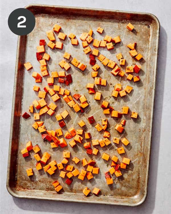 Chopped sweet potatoes on a baking sheet ready for the oven.