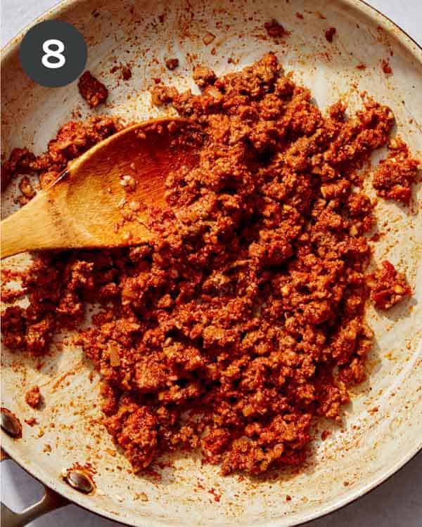 Seasoned ground beef and tomato paste cooking in a skillet.