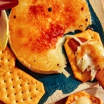 Honey Brûlée Brie on a platter with crackers and celery on the side.