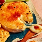 Honey Brûlée Brie on a platter with a knife taking some cheese.