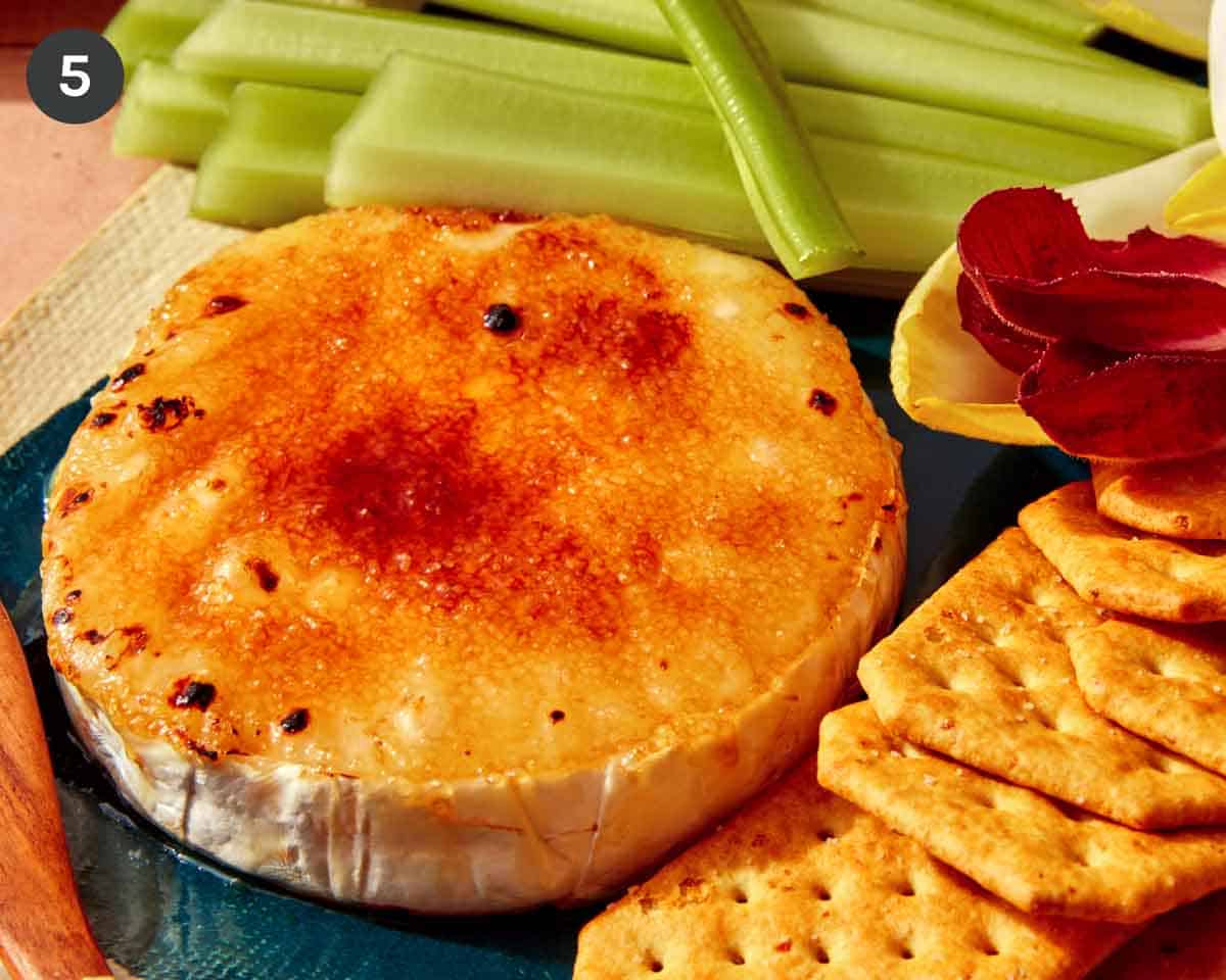Honey Brûlée Brie being served in a platter with crackers and veggies.