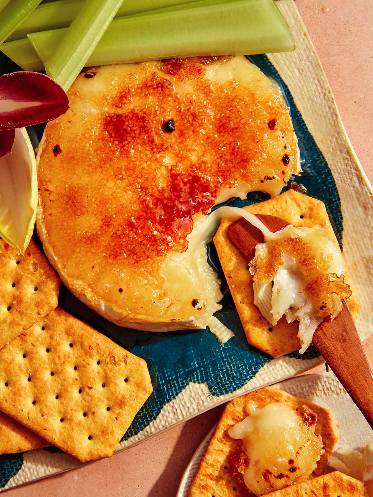 Honey Brûlée Brie on a platter with crackers and celery on the side.