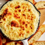 Baked garlic bread dip in a skillet with bread on the side.