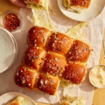 Hawaiian rolls made into a pesto and turkey sandwich being pulled apart with gooey cheese.