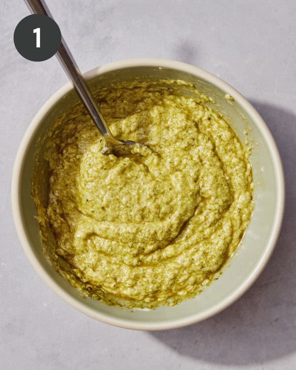 Pesto and mayo being mixed in a bowl.