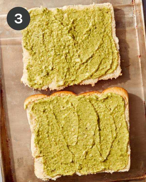 A pesto mayo mixture being spread on a sheet of hawaiian rolls.