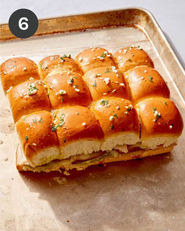 Hawaiian roll sliders on a baking sheet ready to be baked.