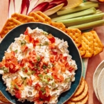 Million dollar dip recipe with crackers and veggies on the side for dipping.