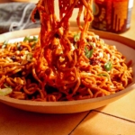 Spicy ramen noodles in a bowl with chopsticks.