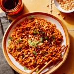 Spicy ramen noodles in a bowl with peanuts and green onions on top.