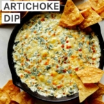 Spinach and artichoke dip in a skillet with chips on the side.