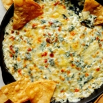 Spinach and artichoke dip in a skillet with chips on the side.
