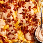 Animal style fries on a baking sheet with dressing on the side.
