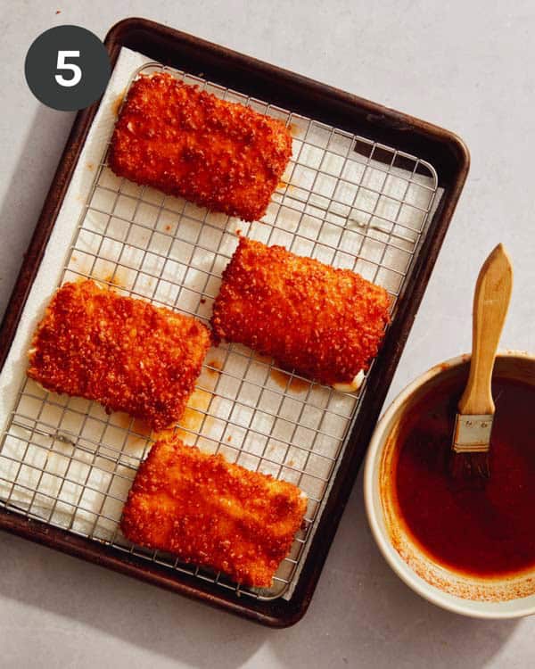 Freshly fried mozzarella sticks with hot honey being brushed on.