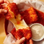 A big cheese pull from a mozzarella stick with hands pulling it apart.