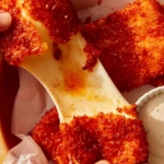 A big cheese pull from a mozzarella stick with hands pulling it apart.
