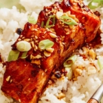 Soy glazed salmon on a bed of rice with a fork.