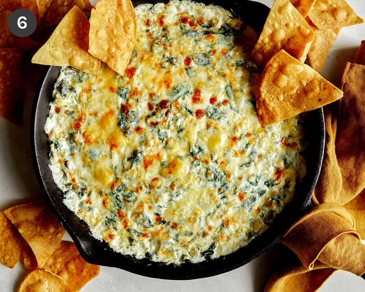 Spinach and artichoke dip in a skillet with tortilla chips on the side. 