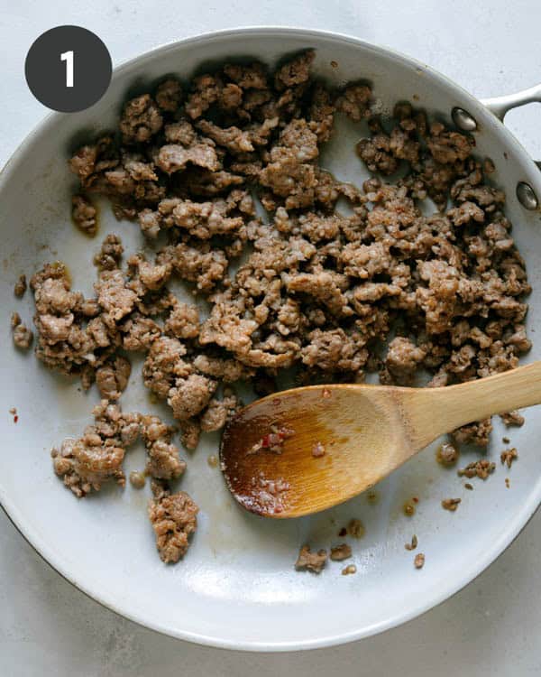 Italian sausage cooking in a skillet for zucchini boats. 