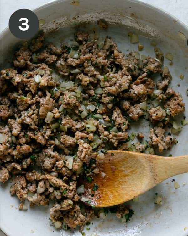 Zucchini boats filling cooking in a skillet.