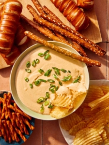 Crock pot beer cheese dip in a bowl with bread and chips all around it.