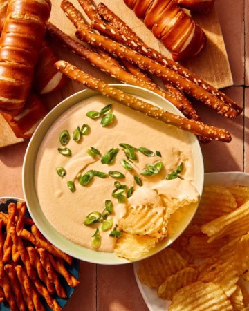 Crock pot beer cheese dip in a bowl with bread and chips all around it.