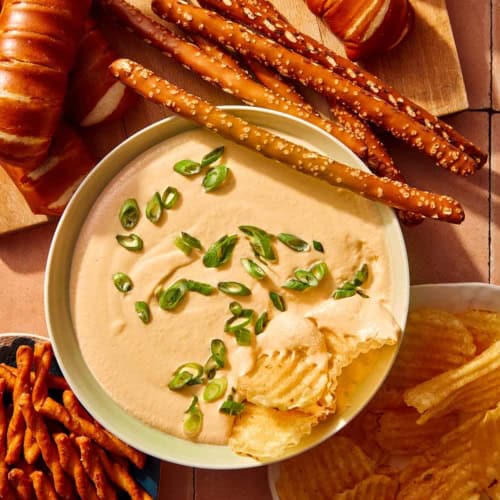 Crock pot beer cheese dip in a bowl with bread and chips all around it.