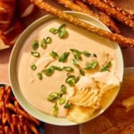 Crock pot beer cheese dip in a bowl with bread and chips all around it.