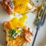A twice baked breakfast potato on a plate cut in half with egg yolk showing.