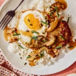 Loco moco up close on a plate with a fork next to it.