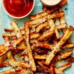 Air fryer french fries on a platter with ketchup and mayo.