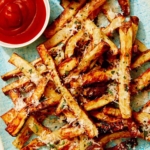 Air fryer french fries on a platter with ketchup and mayo.