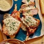 Air fryer pork chops on a platter up close with a sauce over top.