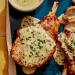 Air fryer pork chops on a platter up close with a sauce over top.