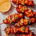 Air fryer bang bang chicken skewers with dipping sauce.