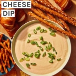 Crock pot beer cheese dip in a bowl being served with pretzels and chips.