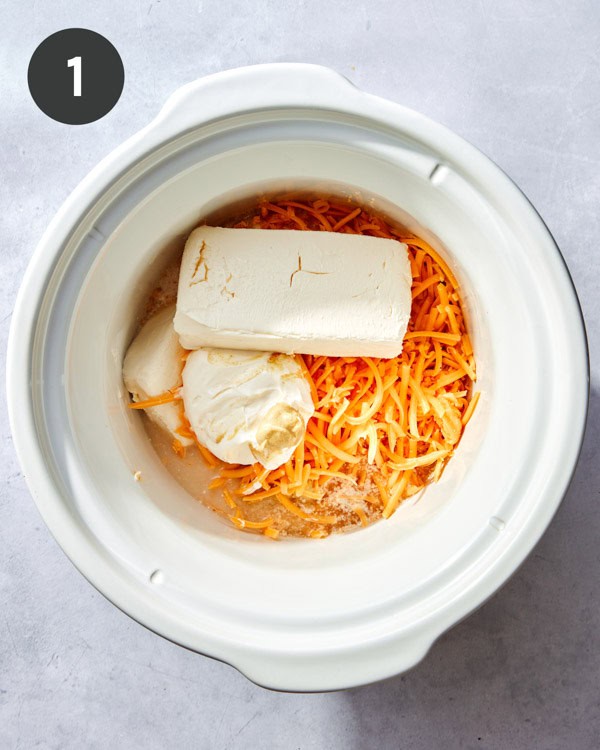 Ingredients for beer cheese dip in a crock pot ready to cook.