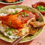 Garlic and ginger braised chicken with a piece of it on a fork.