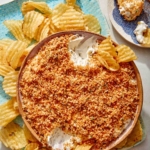 Fried pickle dip in a bowl with potato chips on the side.