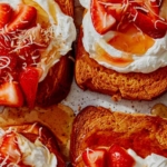 Close up on some slices of honey brick toast with strawberries and whipped cream.